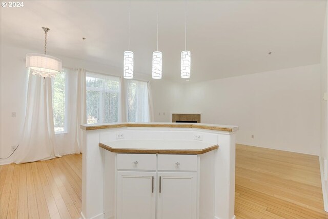 kitchen with hanging light fixtures, a center island, light wood-type flooring, a chandelier, and white cabinets