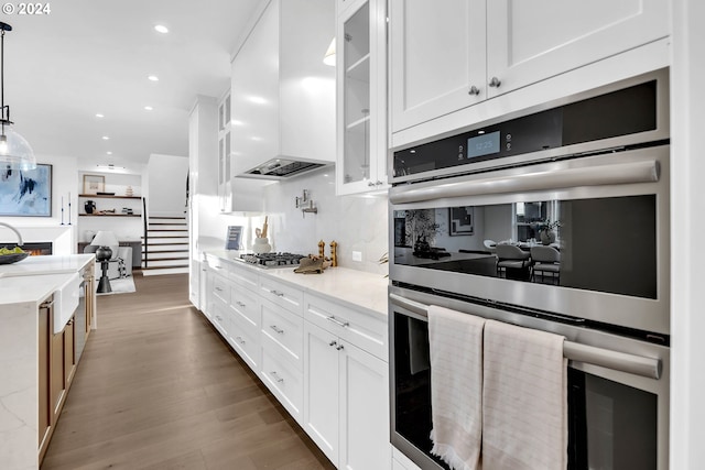 kitchen featuring premium range hood, hanging light fixtures, dark wood-type flooring, white cabinetry, and appliances with stainless steel finishes