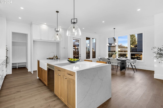 kitchen featuring light stone counters, hanging light fixtures, wood-type flooring, and white cabinetry