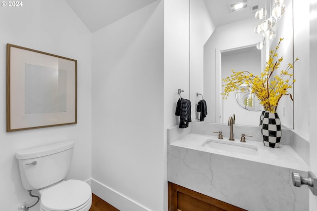 bathroom featuring wood-type flooring, vaulted ceiling, vanity, and toilet