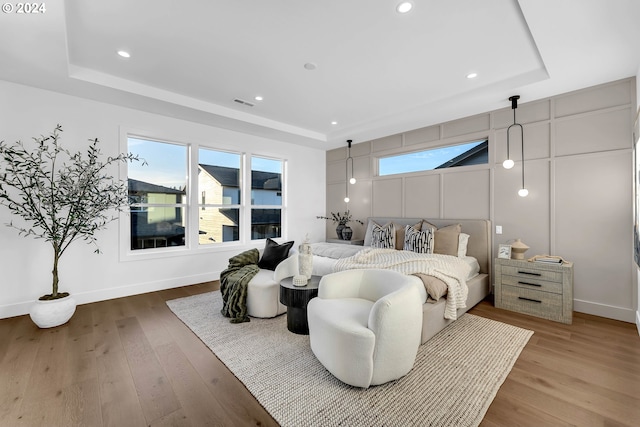 bedroom featuring hardwood / wood-style flooring, a tray ceiling, and a barn door