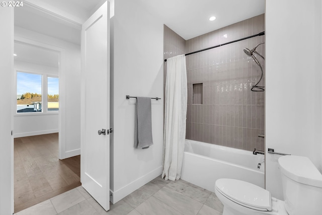 bathroom featuring shower / bathtub combination with curtain and toilet