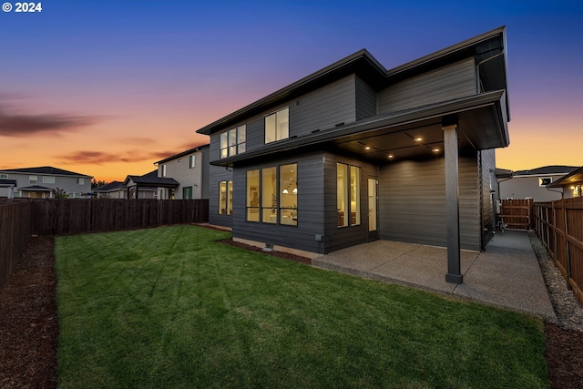 back house at dusk with a yard and a patio