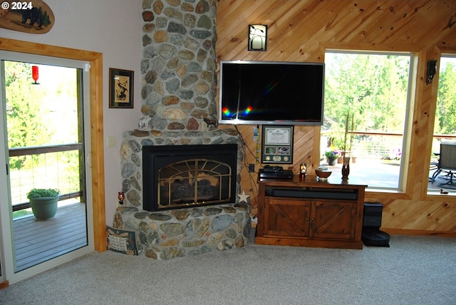 carpeted living room with a fireplace and wood walls