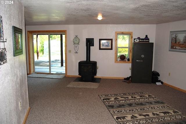 carpeted living room featuring a wood stove and a textured ceiling