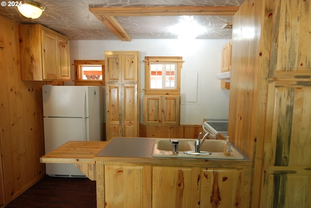 kitchen featuring dark hardwood / wood-style flooring, wooden walls, light brown cabinetry, and white appliances