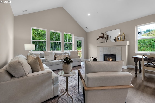 living room with hardwood / wood-style flooring, high vaulted ceiling, a tile fireplace, and plenty of natural light