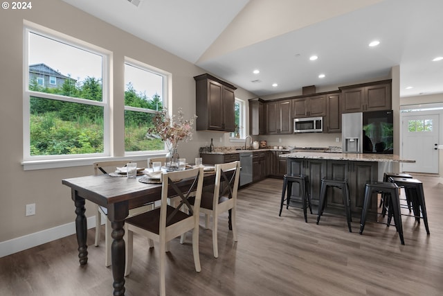 dining room featuring hardwood / wood-style floors, sink, and vaulted ceiling