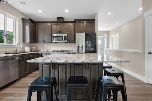 kitchen with a center island, appliances with stainless steel finishes, and a kitchen bar