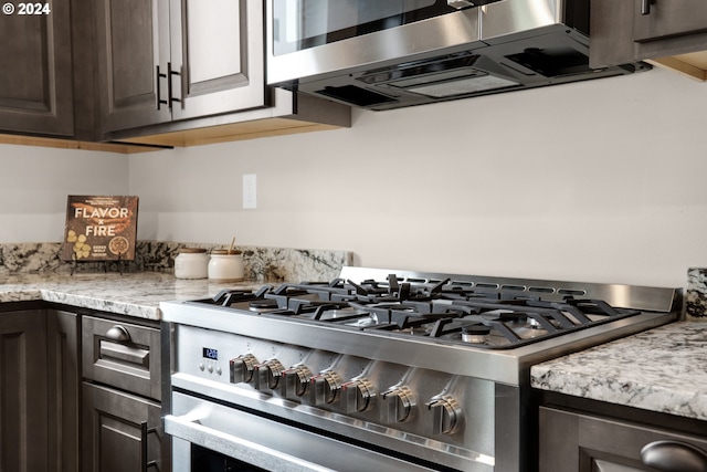 kitchen featuring light stone counters, stainless steel appliances, and dark brown cabinets