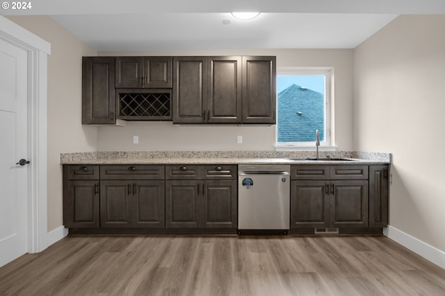 kitchen with dark brown cabinets, stainless steel dishwasher, light wood-type flooring, sink, and light stone counters