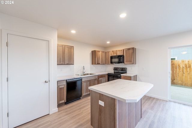 kitchen with tasteful backsplash, sink, black appliances, a center island, and light hardwood / wood-style floors