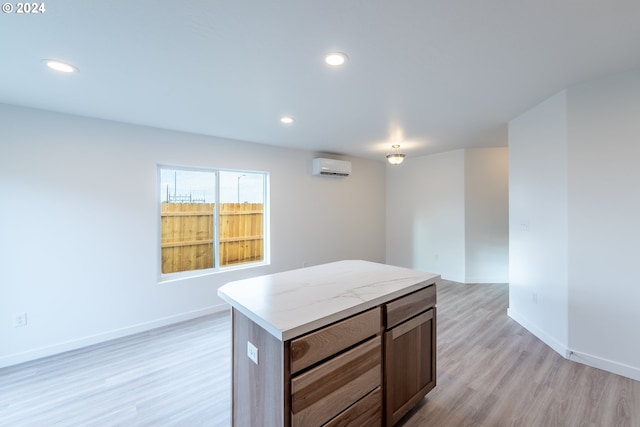 kitchen with a wall unit AC, a center island, and light wood-type flooring