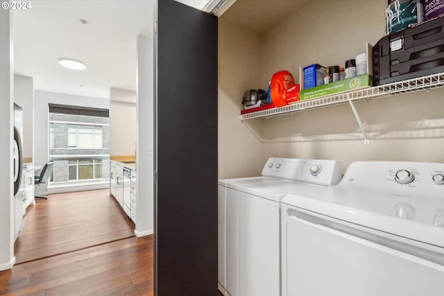 clothes washing area with hardwood / wood-style flooring and independent washer and dryer