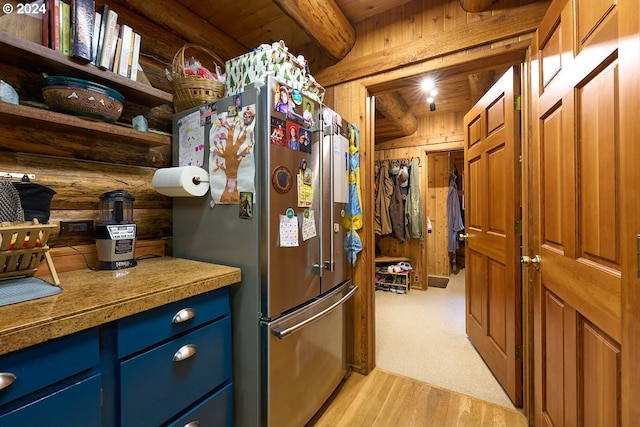 kitchen featuring wooden ceiling, rustic walls, beamed ceiling, and stainless steel refrigerator