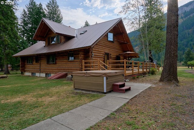 view of side of home featuring a deck with mountain view, a yard, and a hot tub