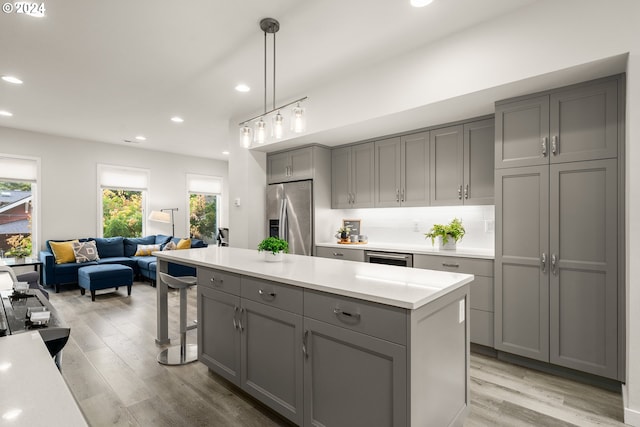 kitchen featuring decorative light fixtures, light hardwood / wood-style floors, gray cabinets, and stainless steel refrigerator with ice dispenser