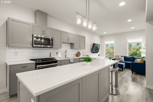 kitchen with gray cabinetry, stainless steel appliances, tasteful backsplash, and light hardwood / wood-style flooring