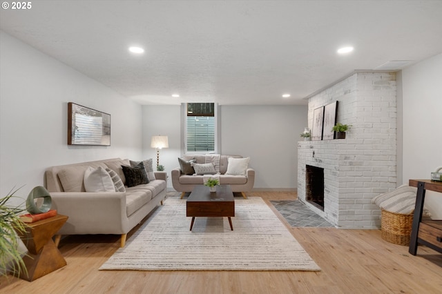 living room with light hardwood / wood-style floors, a textured ceiling, and a fireplace