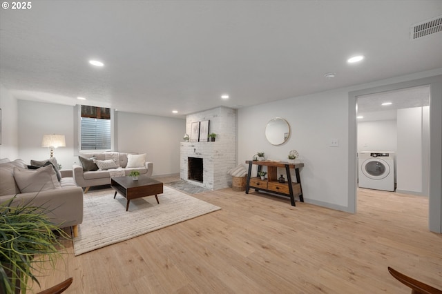 living room with a fireplace, washer / clothes dryer, and light wood-type flooring