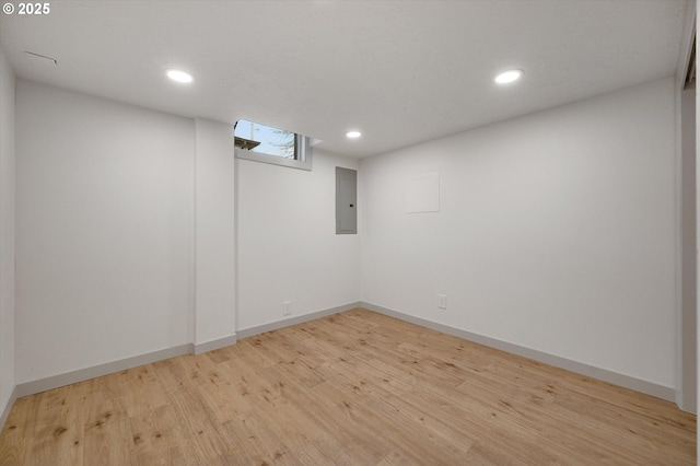 basement with light wood-type flooring and electric panel