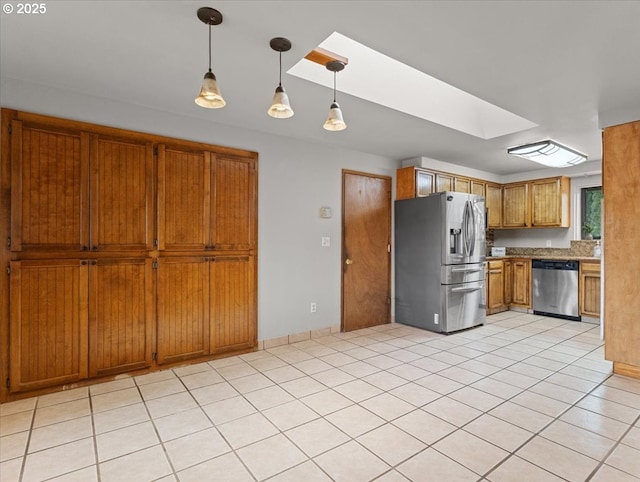 kitchen with pendant lighting, appliances with stainless steel finishes, a skylight, and light tile patterned floors