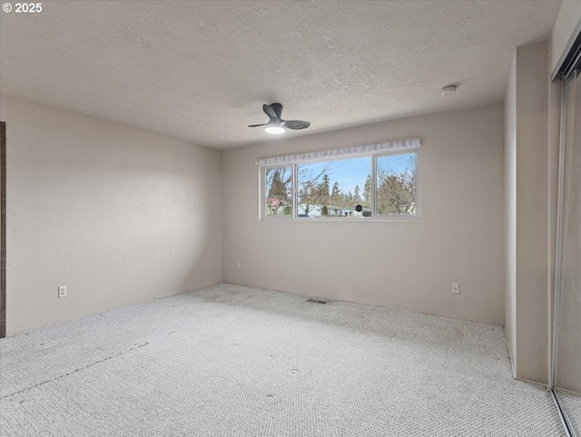 spare room featuring ceiling fan, carpet, and a textured ceiling