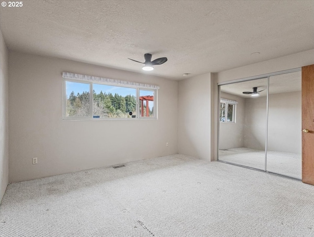 unfurnished bedroom featuring ceiling fan, carpet flooring, a closet, and a textured ceiling