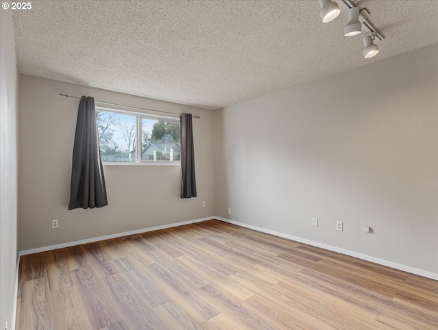 spare room with track lighting, light hardwood / wood-style floors, and a textured ceiling