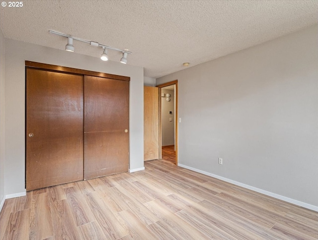 unfurnished bedroom featuring light hardwood / wood-style floors, a closet, and a textured ceiling