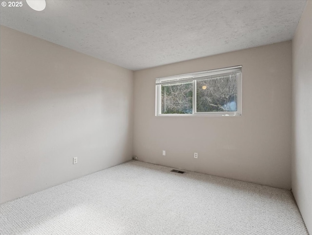 empty room with a textured ceiling and carpet flooring