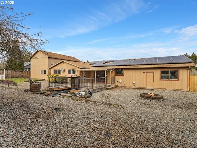 rear view of property featuring a wooden deck and solar panels