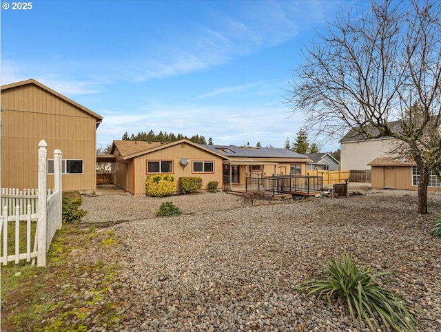 rear view of property with a wooden deck and solar panels