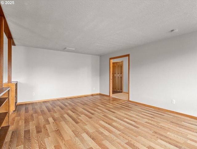 spare room with a textured ceiling and light hardwood / wood-style floors