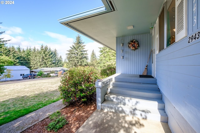 view of exterior entry featuring a lawn