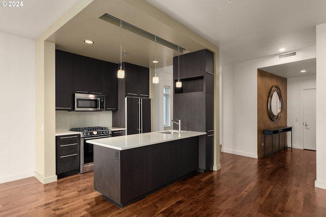 kitchen with dark hardwood / wood-style flooring, hanging light fixtures, stainless steel appliances, and a center island with sink