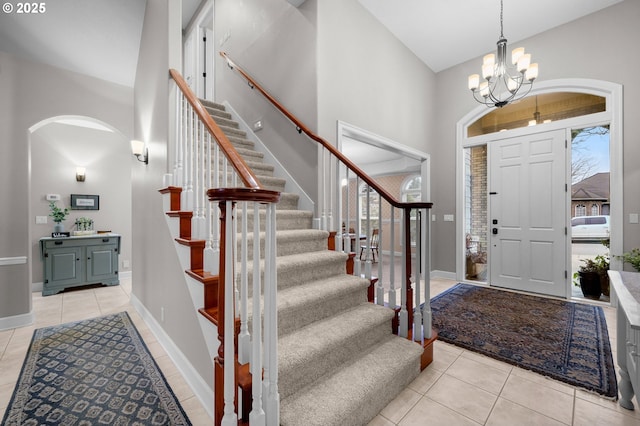 entryway with an inviting chandelier, a towering ceiling, and light tile patterned floors