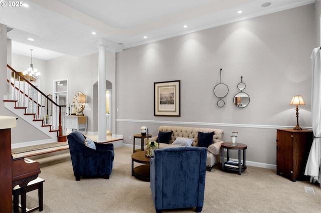 carpeted living room featuring an inviting chandelier, a towering ceiling, ornamental molding, and decorative columns