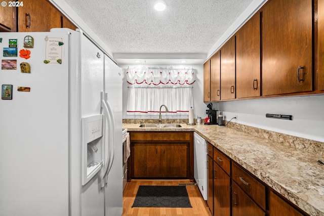 kitchen with white appliances, light hardwood / wood-style flooring, a textured ceiling, and sink