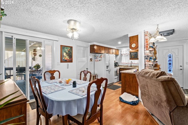 dining area featuring light hardwood / wood-style flooring, a textured ceiling, sink, and ceiling fan