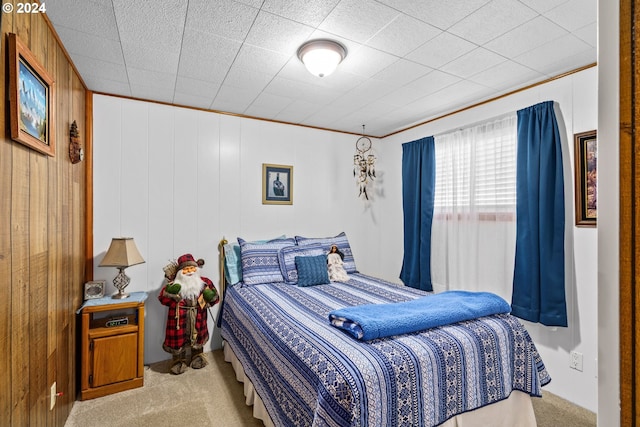 bedroom featuring ornamental molding, wood walls, and light colored carpet