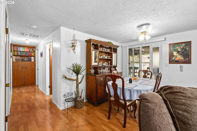 dining area featuring a textured ceiling, wood-type flooring, and ceiling fan