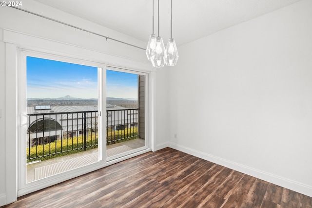 spare room featuring wood-type flooring and an inviting chandelier