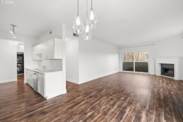 kitchen with stacked washing maching and dryer, tasteful backsplash, pendant lighting, dishwasher, and white cabinetry