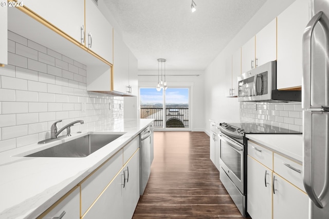 kitchen with sink, stainless steel appliances, tasteful backsplash, decorative light fixtures, and white cabinets