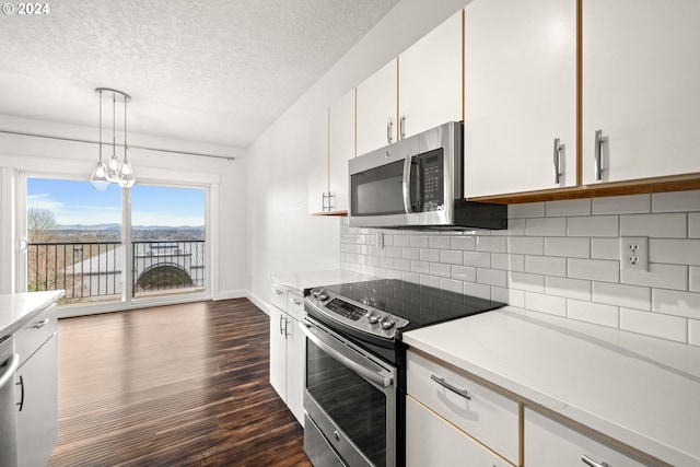 kitchen featuring stainless steel appliances, dark wood-type flooring, a notable chandelier, white cabinets, and hanging light fixtures