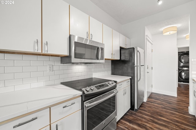 kitchen featuring appliances with stainless steel finishes, dark hardwood / wood-style flooring, stacked washing maching and dryer, backsplash, and white cabinets