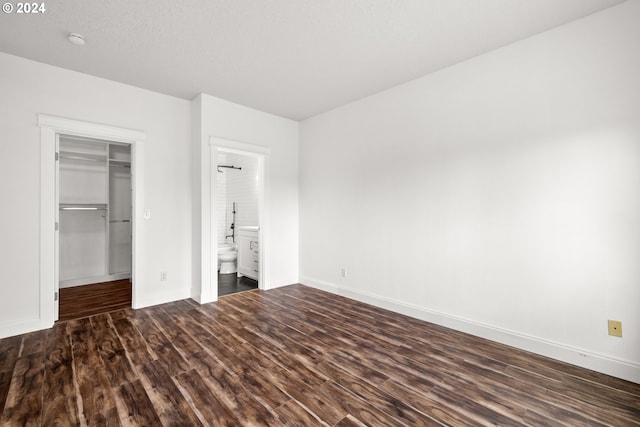 unfurnished bedroom featuring ensuite bath, a closet, and dark hardwood / wood-style flooring