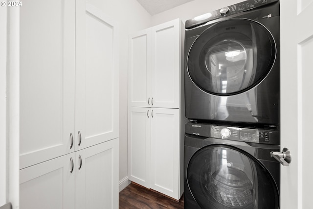 washroom with cabinets, dark hardwood / wood-style floors, and stacked washer / drying machine