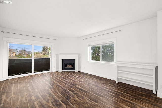 unfurnished living room with dark hardwood / wood-style flooring and plenty of natural light